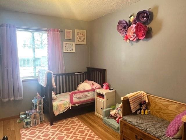 bedroom featuring hardwood / wood-style flooring, multiple windows, and a textured ceiling