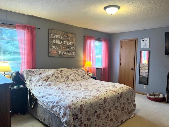 bedroom with light colored carpet and a textured ceiling