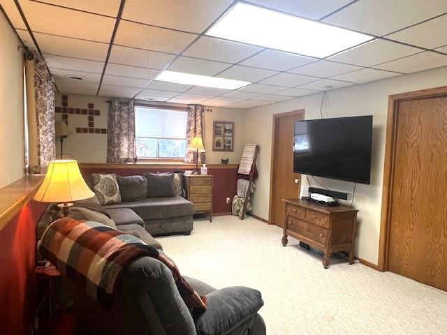 living room with a paneled ceiling and carpet flooring