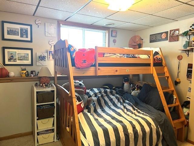 bedroom featuring a drop ceiling and carpet flooring