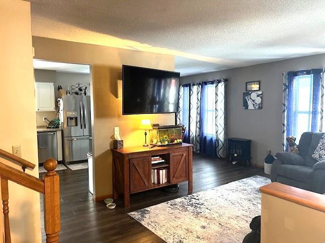 living room featuring a textured ceiling, dark hardwood / wood-style flooring, and a wealth of natural light