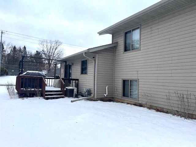 view of snowy exterior featuring a deck and central air condition unit