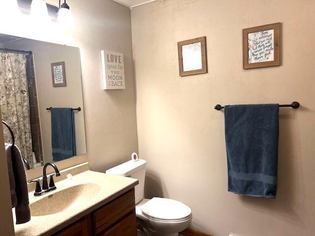 bathroom with toilet, vanity, and curtained shower