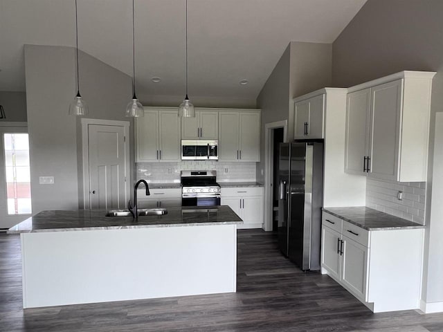 kitchen with white cabinetry, stainless steel appliances, sink, hanging light fixtures, and a kitchen island with sink