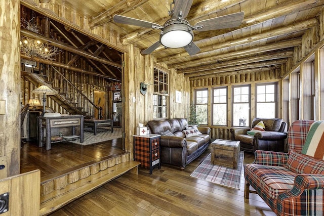 living area with ceiling fan, beam ceiling, dark hardwood / wood-style flooring, wooden ceiling, and wood walls