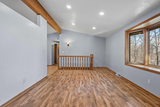 spare room featuring lofted ceiling with beams and hardwood / wood-style floors