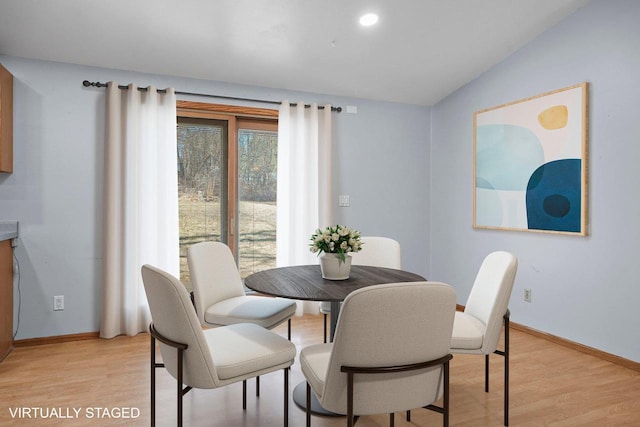 dining area featuring vaulted ceiling and light hardwood / wood-style flooring