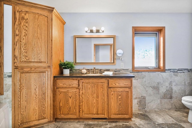 bathroom with vanity, tile walls, and toilet