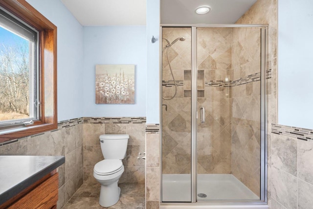 bathroom featuring walk in shower, vanity, toilet, and tile walls