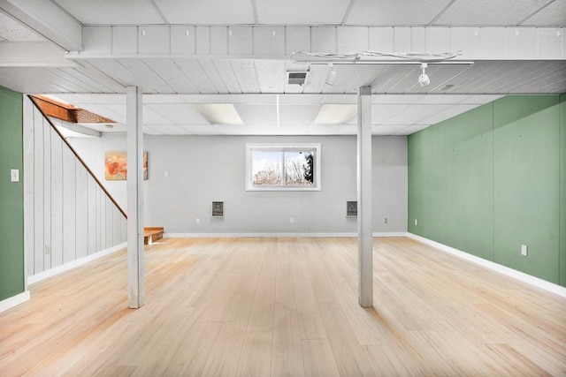 basement featuring a drop ceiling and light hardwood / wood-style floors