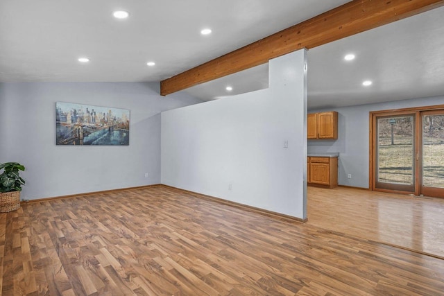 unfurnished living room featuring vaulted ceiling with beams and light hardwood / wood-style floors