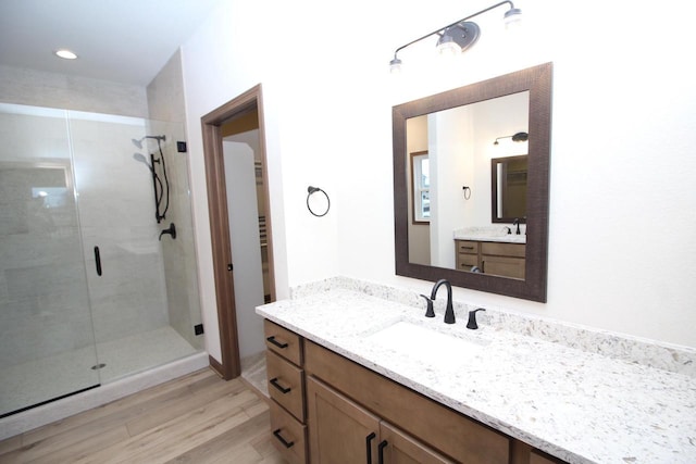 bathroom with walk in shower, vanity, and hardwood / wood-style flooring