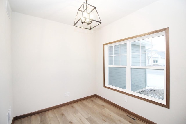 spare room with wood-type flooring and an inviting chandelier