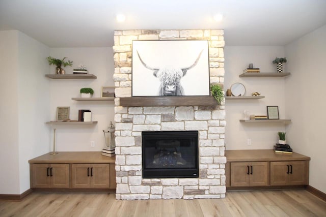 living room with a stone fireplace and light hardwood / wood-style flooring