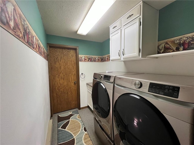 washroom with a textured ceiling, washing machine and clothes dryer, and cabinets