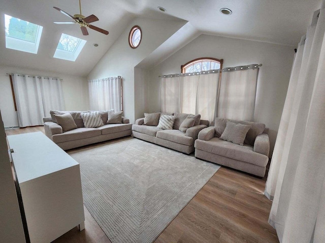 living room with ceiling fan, a skylight, high vaulted ceiling, and hardwood / wood-style floors