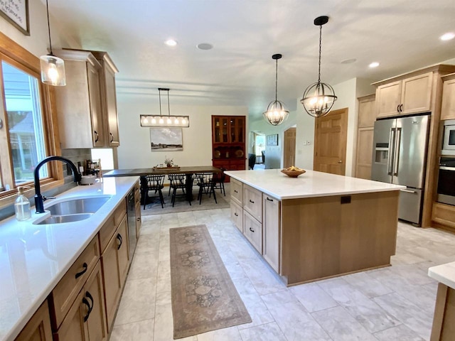 kitchen featuring decorative light fixtures, a center island, sink, appliances with stainless steel finishes, and light brown cabinets