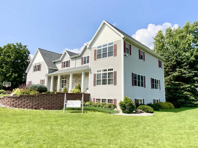 rear view of property with covered porch and a yard