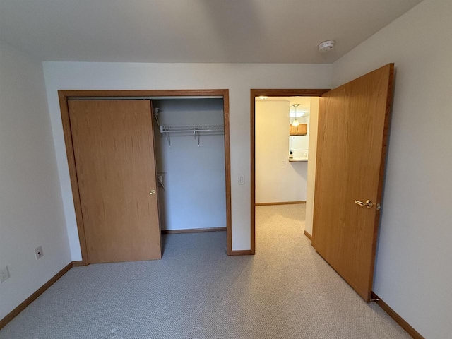 unfurnished bedroom with light carpet, a closet, and refrigerator