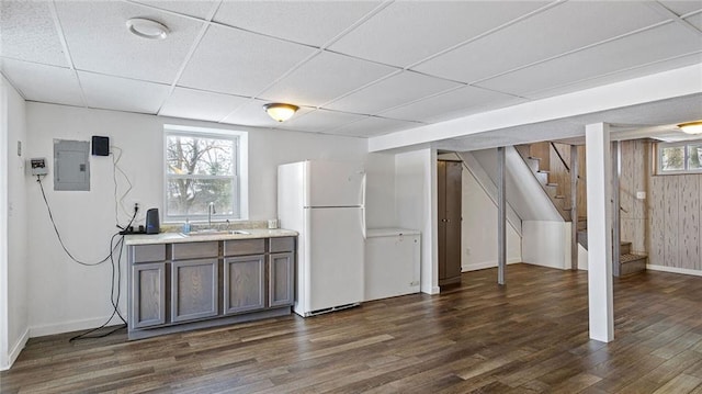 interior space with white refrigerator, sink, plenty of natural light, a drop ceiling, and electric panel