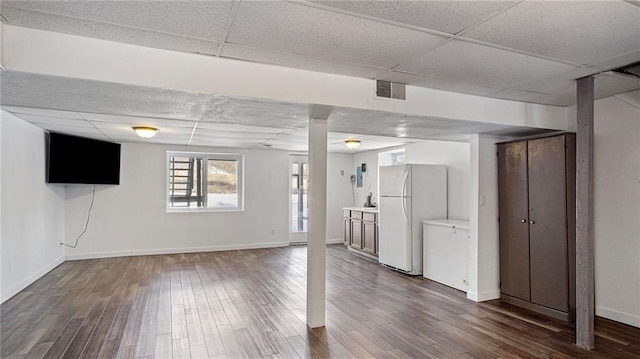 basement with a paneled ceiling, dark wood-type flooring, and white refrigerator