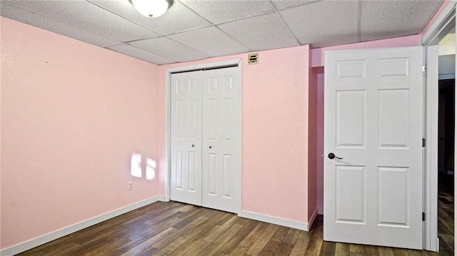 unfurnished bedroom featuring a paneled ceiling, a closet, and hardwood / wood-style floors