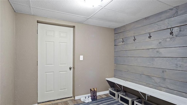 mudroom featuring a drop ceiling, wooden walls, and hardwood / wood-style floors