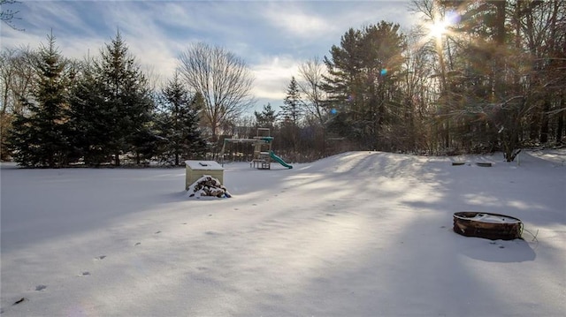 snowy yard featuring a playground and a fire pit