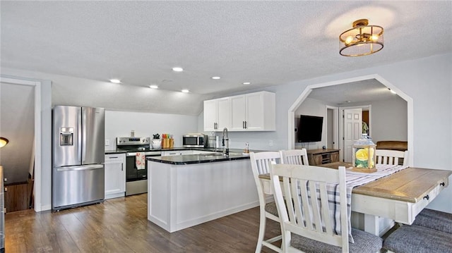 kitchen with white cabinetry, kitchen peninsula, stainless steel appliances, and vaulted ceiling