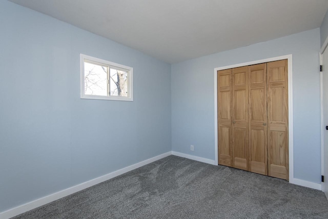 unfurnished bedroom with a closet and dark colored carpet