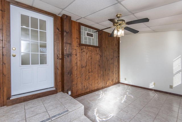 entryway featuring a paneled ceiling, wood walls, and ceiling fan