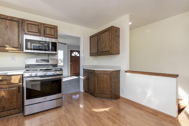 kitchen with light wood-type flooring, stainless steel appliances, and dark brown cabinets