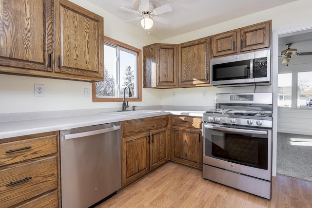 kitchen with ceiling fan, stainless steel appliances, light hardwood / wood-style flooring, and sink