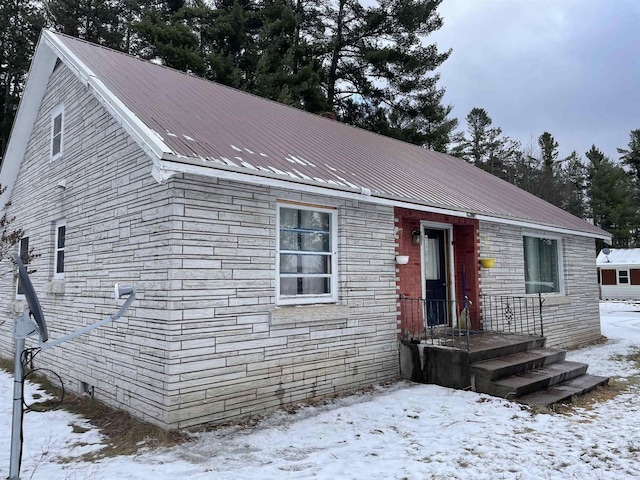 single story home with stone siding and metal roof