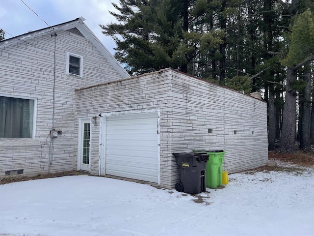 snow covered property with crawl space and a garage