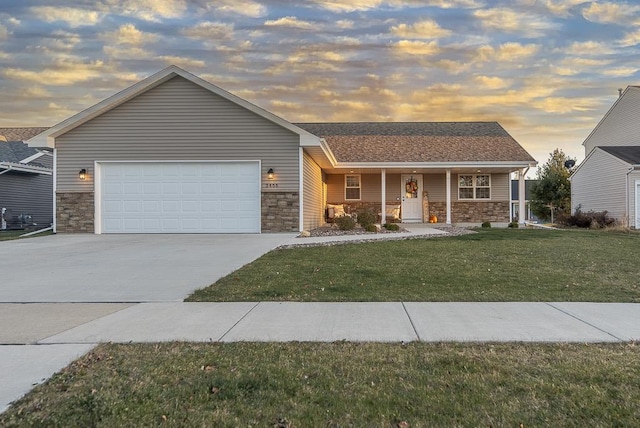 single story home with a garage, a porch, and a lawn