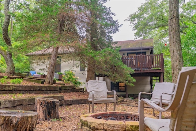 back of house with a wooden deck and a fire pit