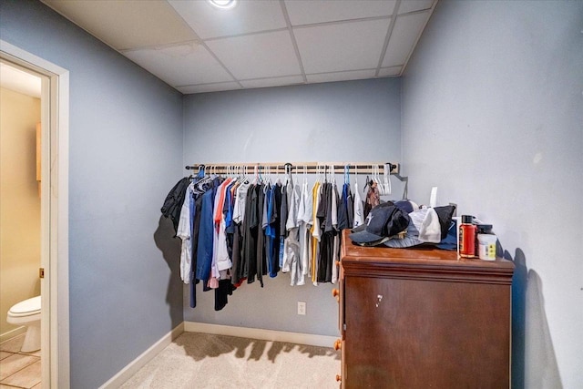 spacious closet with light colored carpet and a drop ceiling