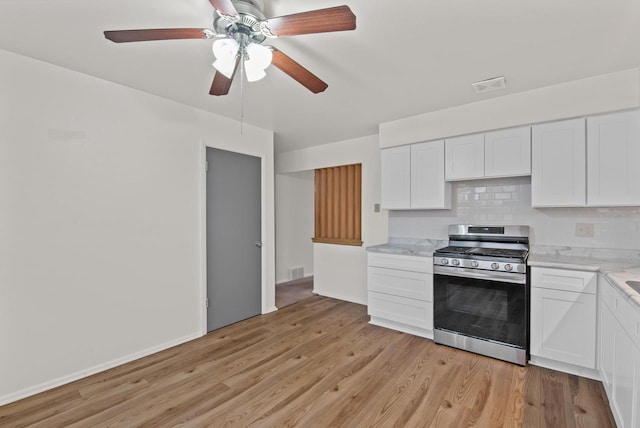 kitchen with stainless steel gas range, white cabinetry, decorative backsplash, light hardwood / wood-style floors, and ceiling fan