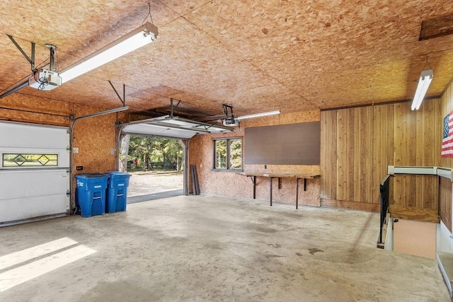 garage featuring a garage door opener and wooden walls