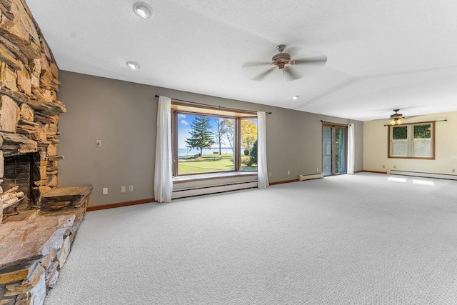 unfurnished living room featuring ceiling fan, a baseboard heating unit, a fireplace, and carpet flooring