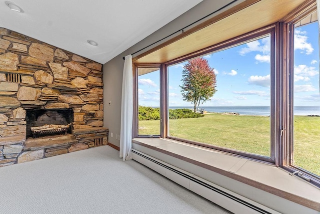 unfurnished living room with carpet floors, lofted ceiling, a baseboard heating unit, a stone fireplace, and a water view