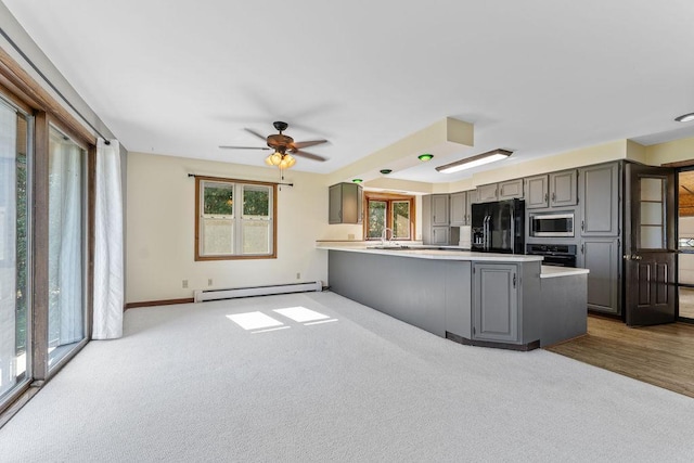 kitchen featuring a baseboard radiator, gray cabinets, kitchen peninsula, black fridge with ice dispenser, and stainless steel microwave