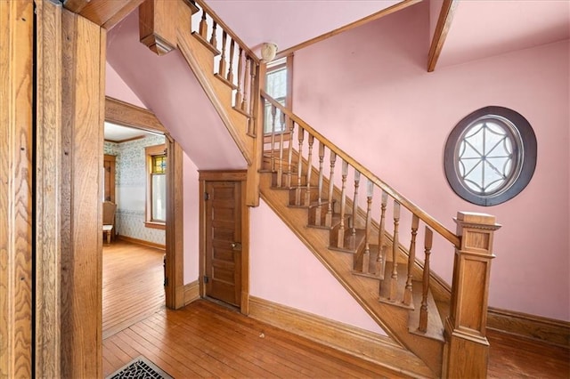 stairs with hardwood / wood-style floors and a healthy amount of sunlight