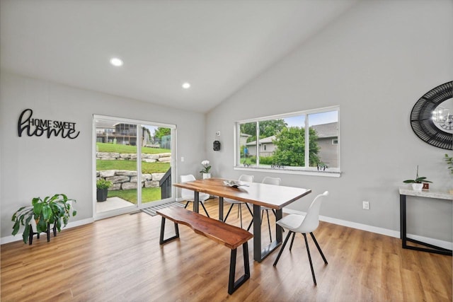 dining room with light hardwood / wood-style floors, plenty of natural light, and high vaulted ceiling