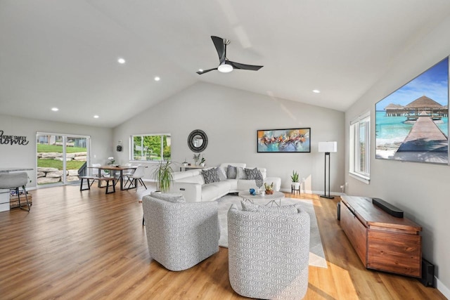 living room featuring ceiling fan, light hardwood / wood-style flooring, and vaulted ceiling