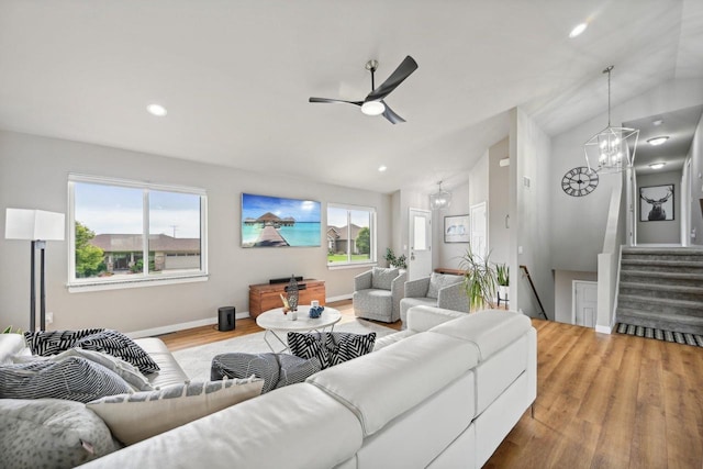 living room featuring vaulted ceiling, ceiling fan with notable chandelier, and hardwood / wood-style floors