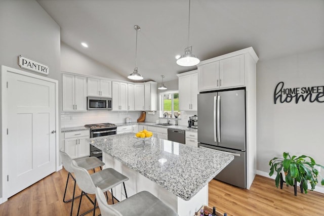 kitchen featuring white cabinetry, appliances with stainless steel finishes, decorative backsplash, pendant lighting, and a center island