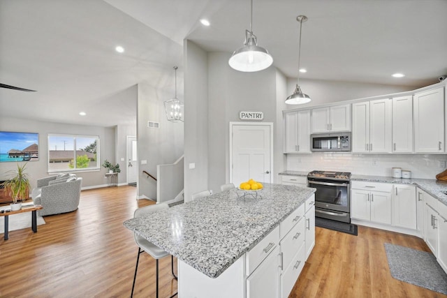 kitchen featuring decorative light fixtures, backsplash, a center island, appliances with stainless steel finishes, and white cabinets