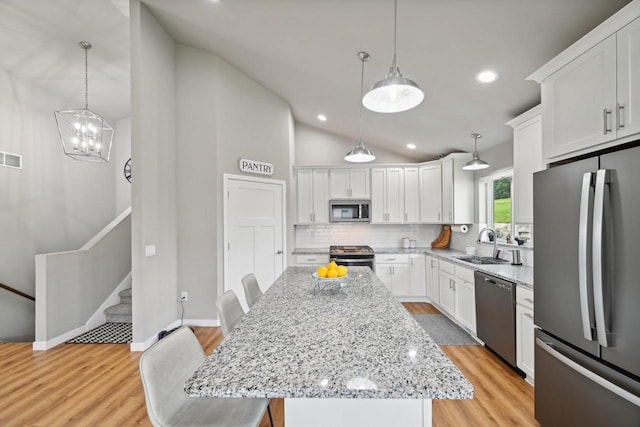 kitchen with stainless steel appliances, tasteful backsplash, a kitchen breakfast bar, white cabinets, and a center island